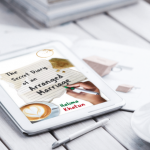 E-reader showing cover for The Secret Diary of an Arranged Marriage by Halima Khatun, lying on top of and beside leaflets and a pen on a white wooden slatted surface beside half a cup of black coffee.